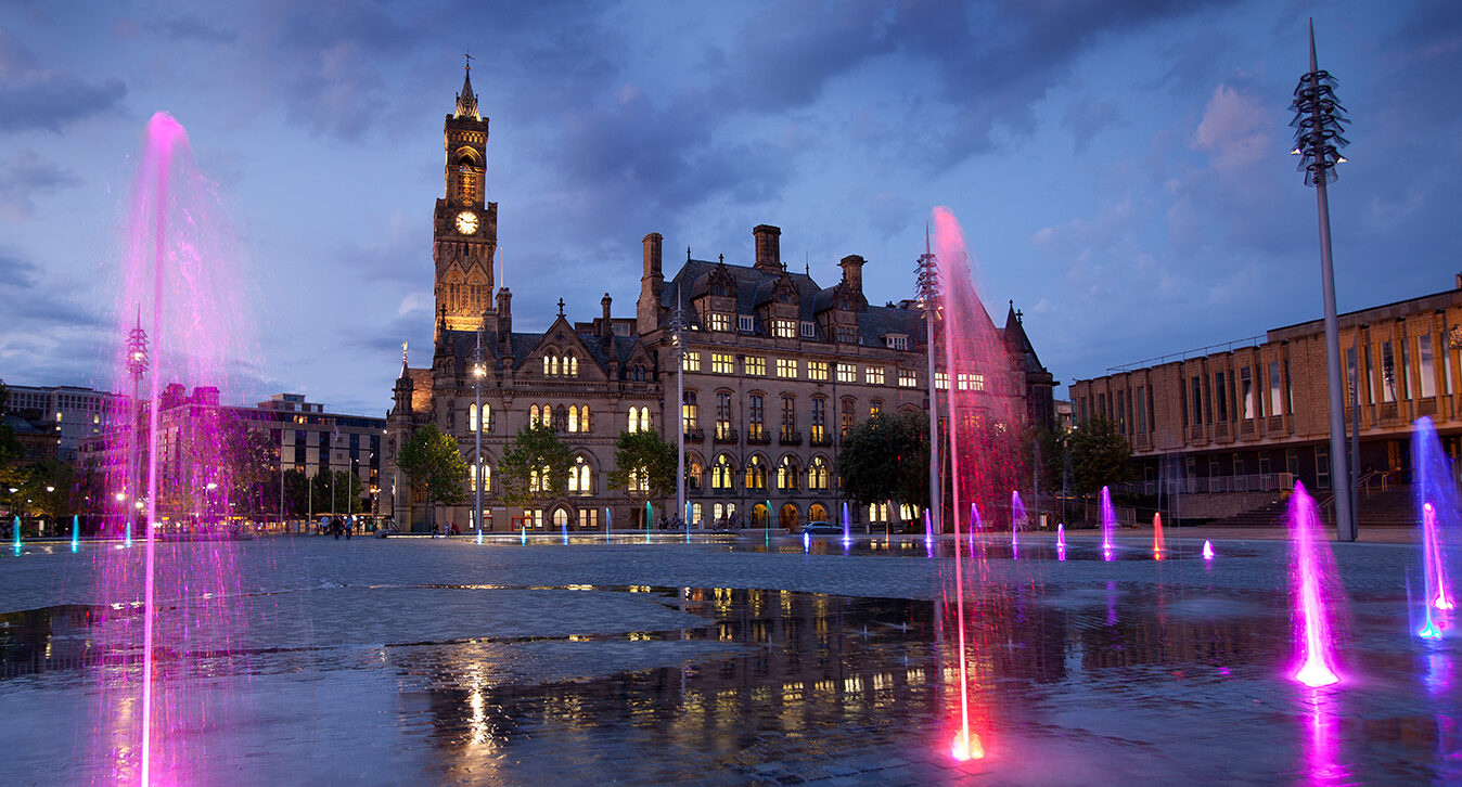 Centenary Square in Bradford at dusk lit up with columns of pink and red light