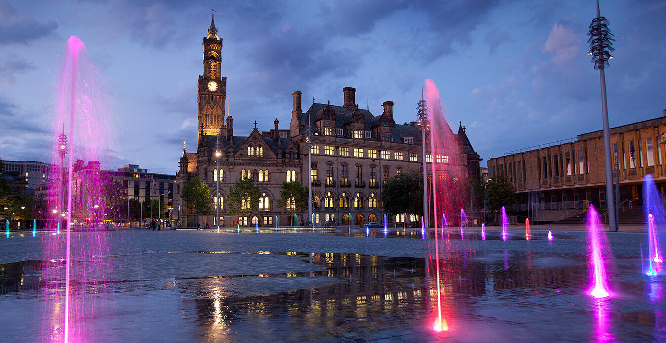 Centenary Square in Bradford at dusk lit up with columns of pink and red light