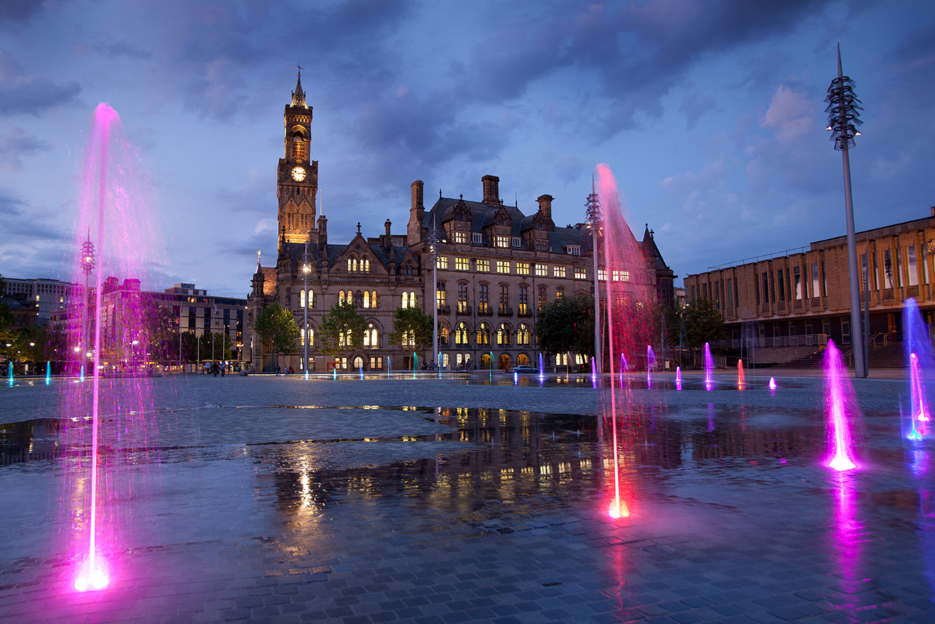 Centenary Square in Bradford at dusk lit up with columns of pink and red light
