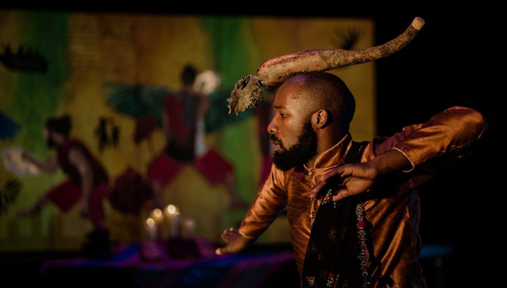 Photo from BPH Make Work Artist, Yuvel Soria's performance, AJAYU Transitorio. Image feature's a black man in traditional Bolivian dress holding a dance pose.