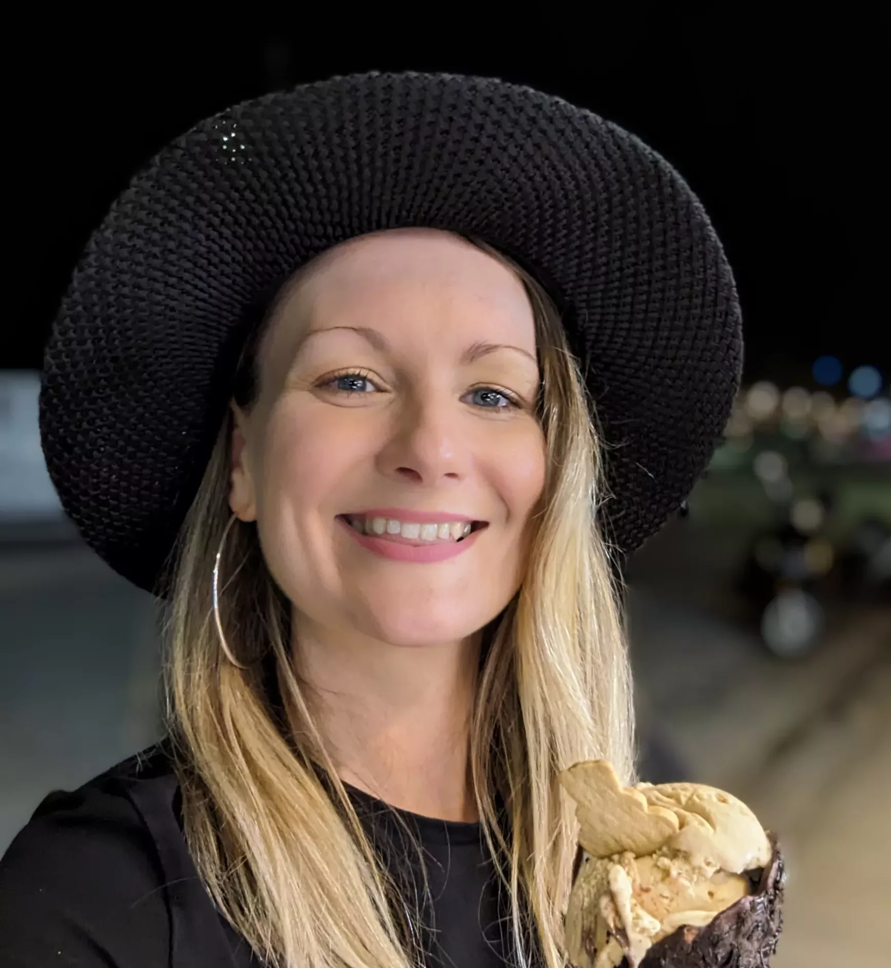 Frances Murphy is a white woman with blonde hair and blue eyes. She is holding an ice cream whilst smiling at the camera.