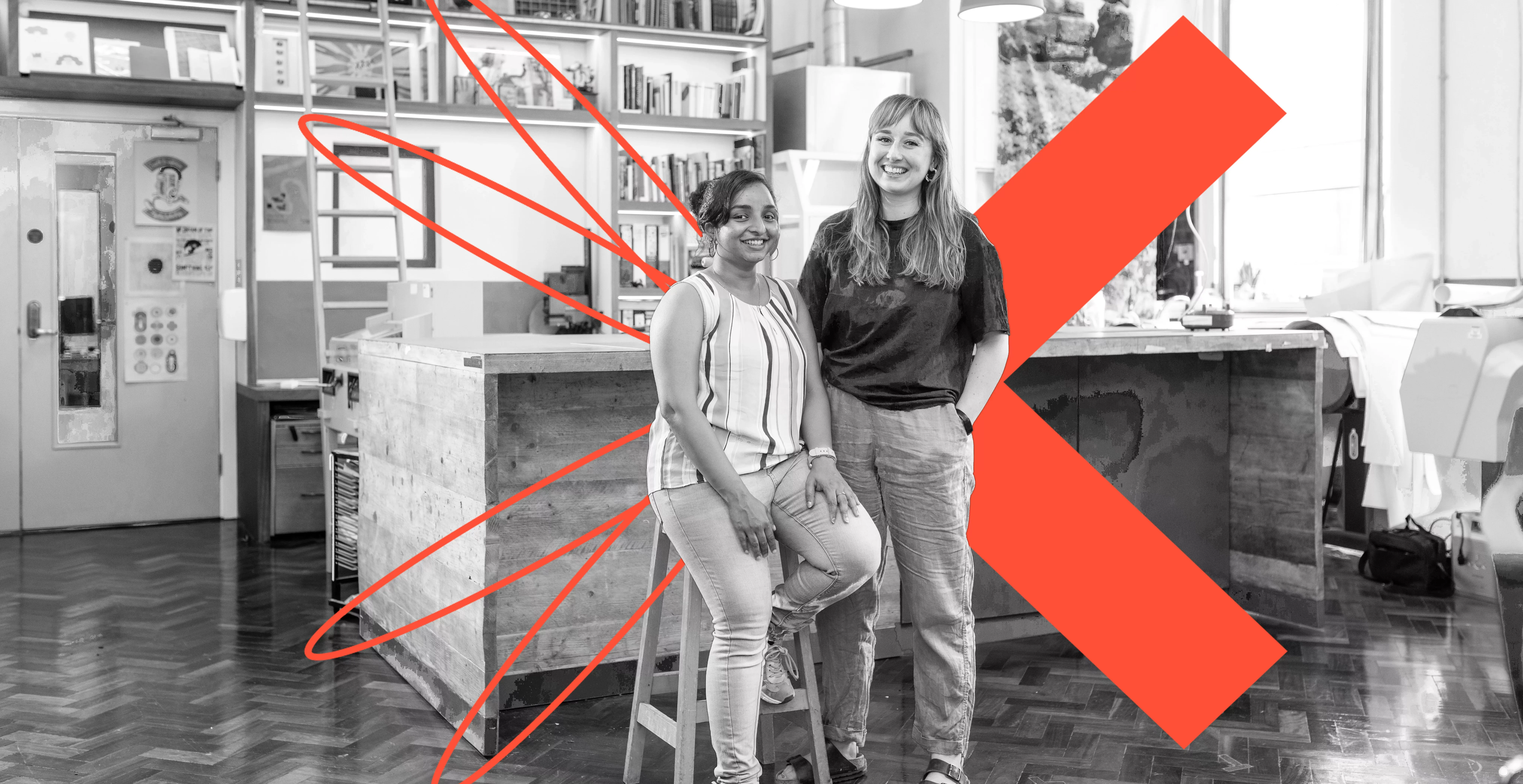 Two women in a lab with the orange X Leeds Creative Labs logo behind them