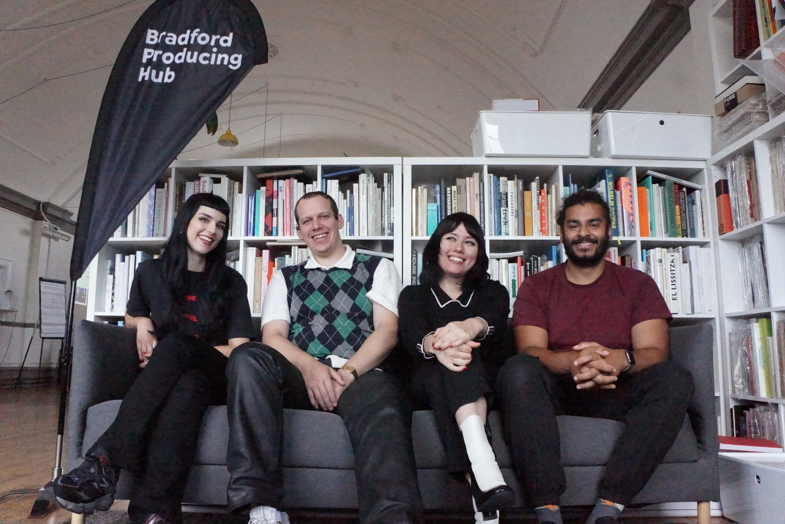 La Rissa, Lloydfears, Hannah Hu and Dan Loops sat on a couch next to a Bradford Producing Hub Flag