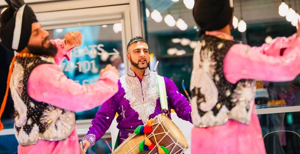 Davinder Singh playing dhol in traditional Punjabi dress.