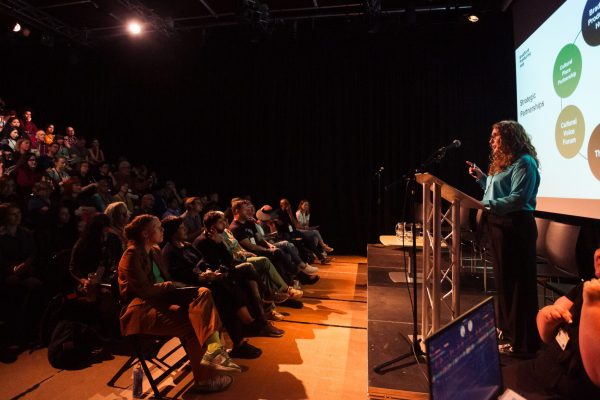 Exec. Director of Bradford Producing Hub speaking at a lectern to conference delegates