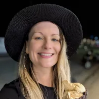 Frances Murphy is a white woman with blonde hair and blue eyes. She is holding an ice cream whilst smiling at the camera.
