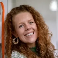 Kirsty Taylor is a white woman with long curly ginger hair.